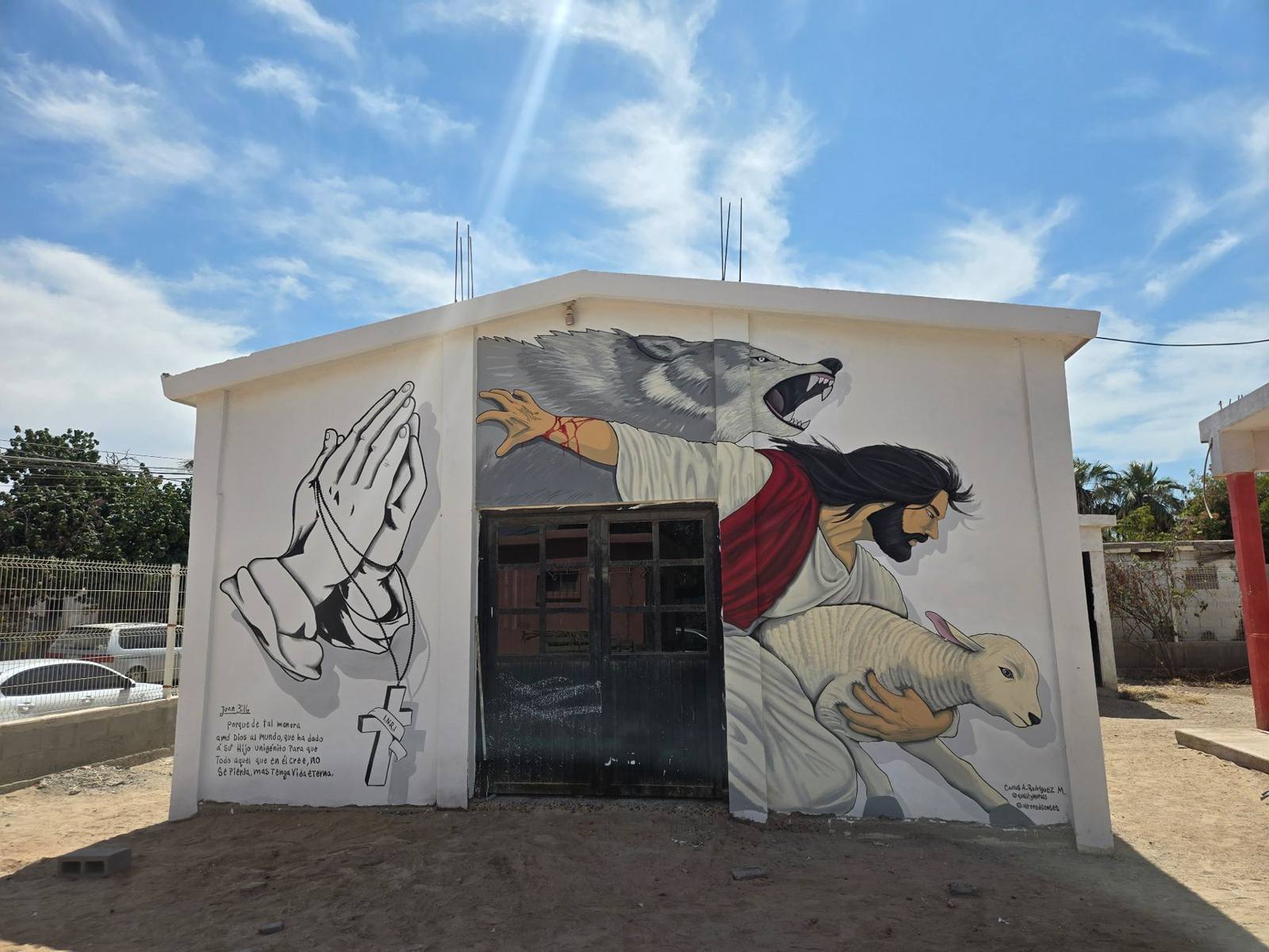 Good Shepherd mural with praying hands and John 3:16 painted across a chapel exterior