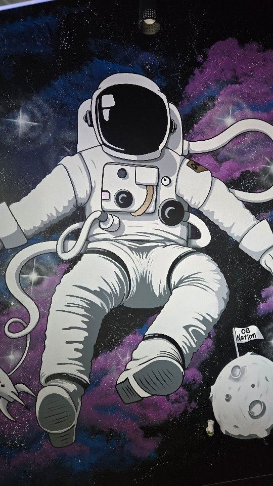 Painted astronaut floating in a purple galaxy on a children's room wall