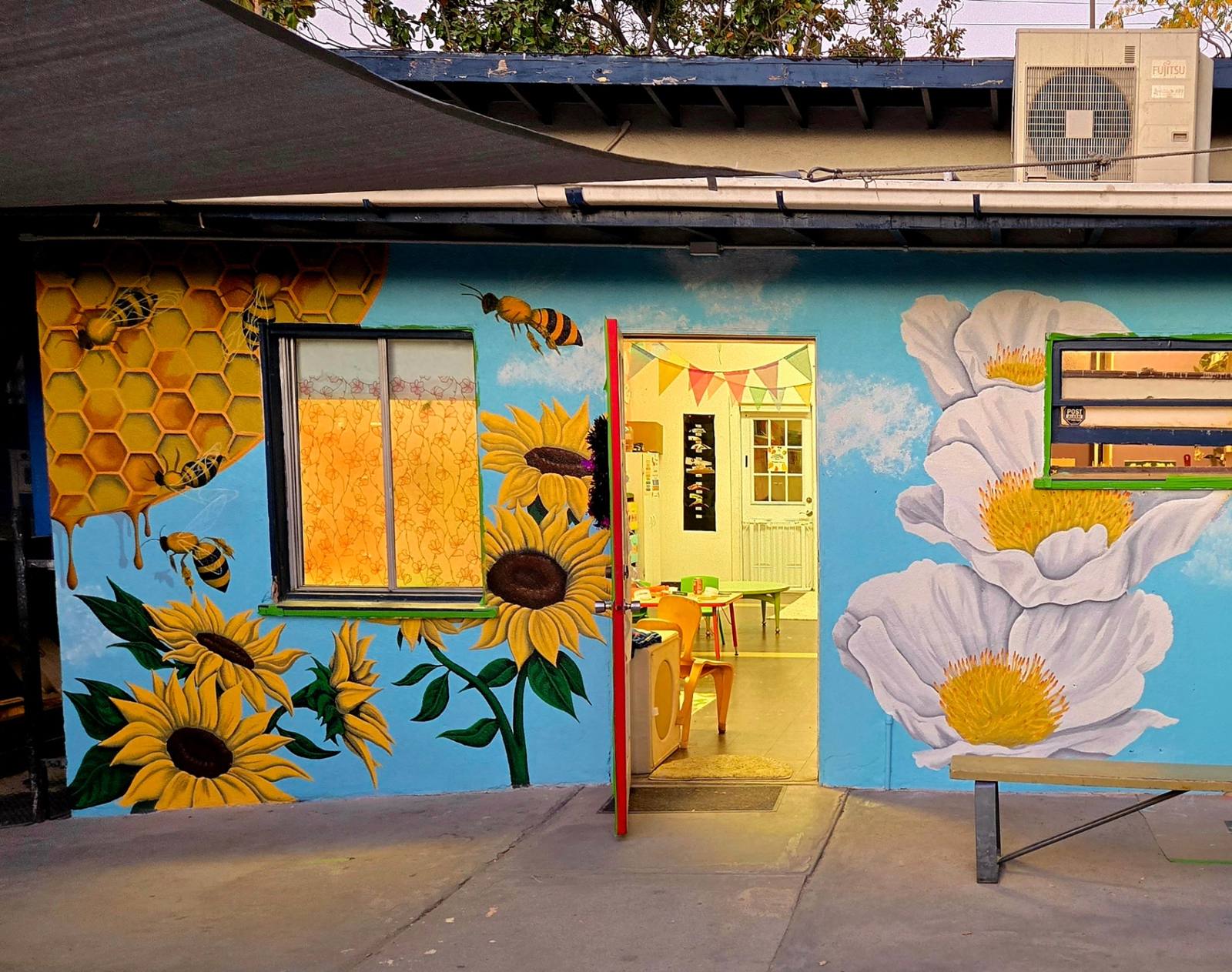 Bright sunflower, honeycomb and bee mural wrapping a children’s ministry entrance
